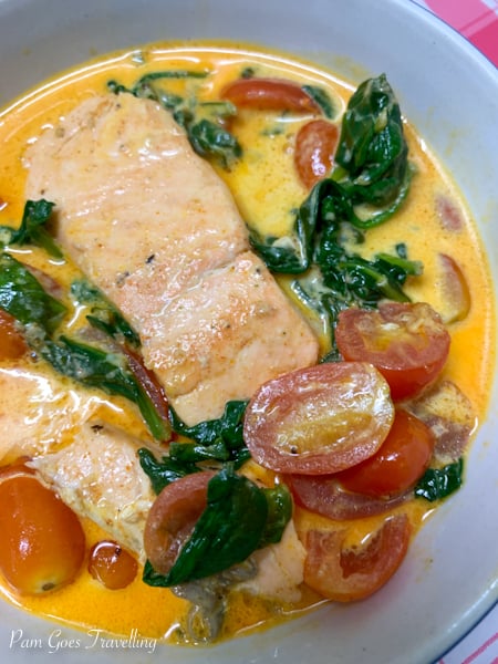 A dish of salmon with tomatoes and spinach. 